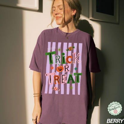 Person wearing a purple 'Trick or Treat' t-shirt against a neutral wall.