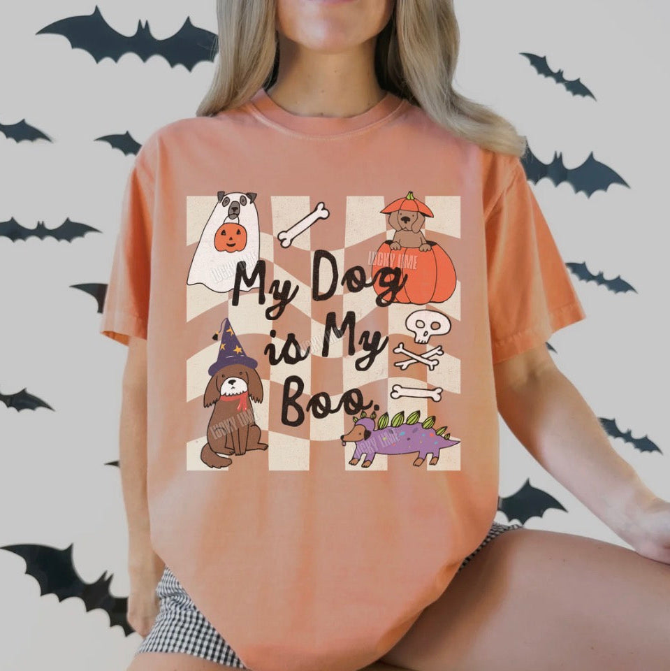 Person wearing a terracotta t-shirt with Halloween-themed dog illustrations and text on a light gray background with bats.