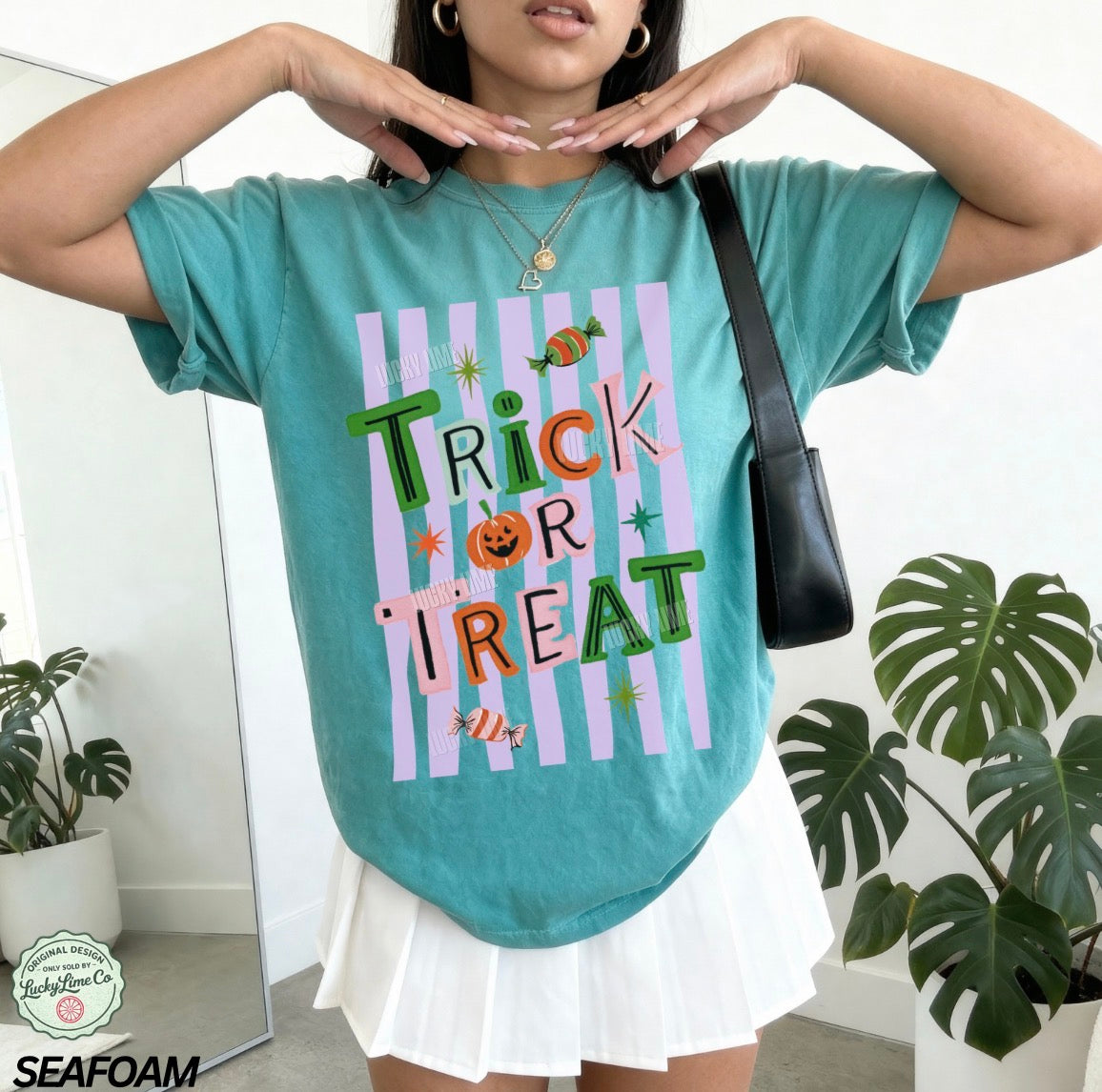 Person wearing a teal 'Trick or Treat' shirt with Halloween-themed design, standing indoors.