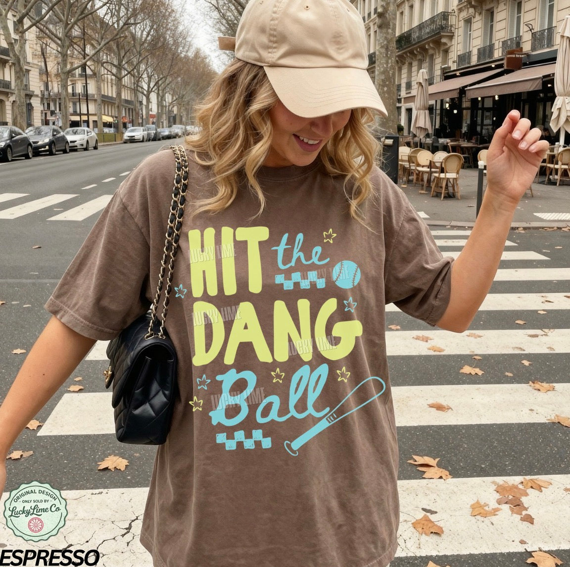 Woman wearing a brown shirt with the words “Hit the Dang ball” with baseball graphics