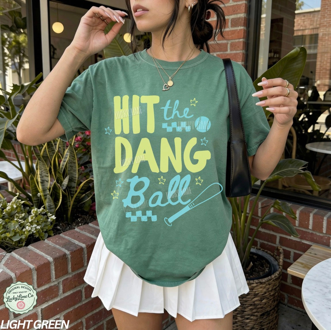 Woman wearing a green tshirt with the words “Hit the Dang ball” with baseball graphics