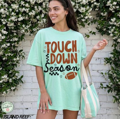 Woman wearing a 'Touchdown Season' t-shirt with floral and brick wall background