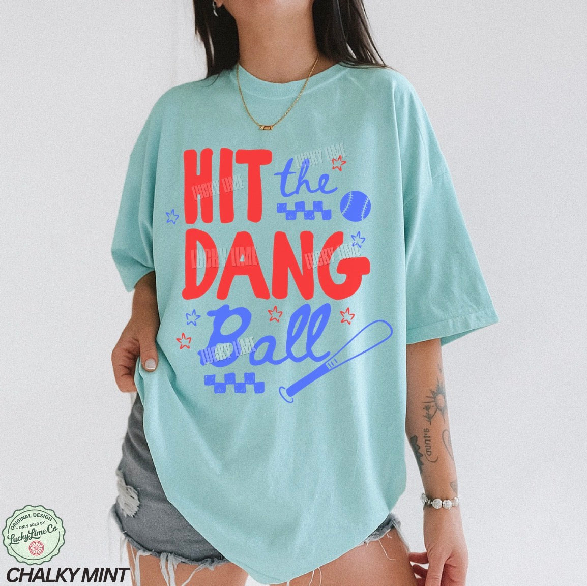 Light blue t-shirt with colorful text and graphics worn by a person on a plain background