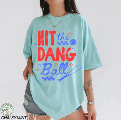Light blue t-shirt with colorful text and graphics worn by a person on a plain background