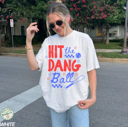 Person wearing a white t-shirt with colorful text and graphics, standing on a street.