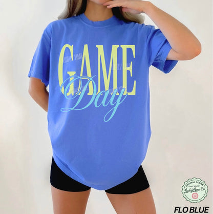 Woman wearing a bright blue tshirt with the words “Game Day” on a white background