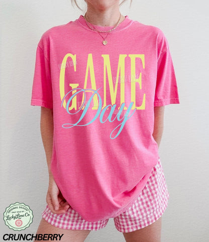 Woman wearing a bright pink  tshirt with the words “Game Day”