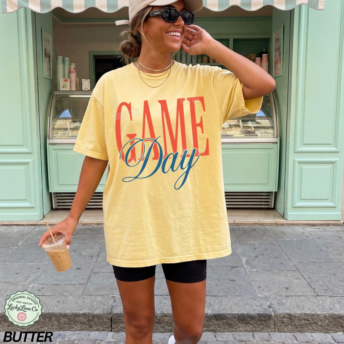 Woman wearing a yellow 'GAME Day' t-shirt in front of a store.