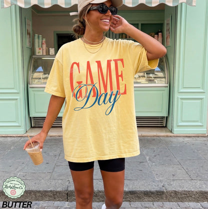 Woman wearing a yellow 'GAME Day' t-shirt in front of a store.
