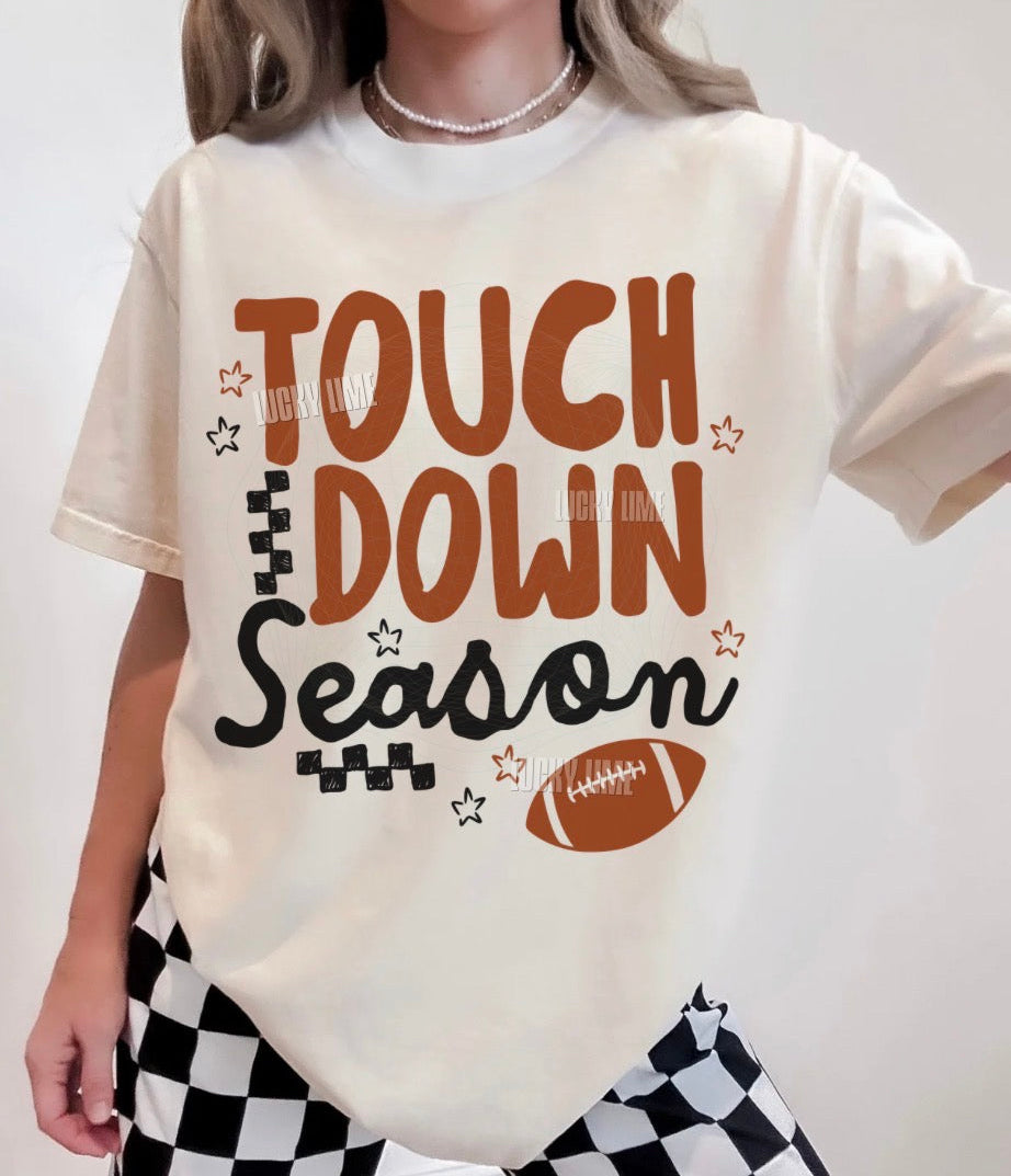Person wearing a t-shirt with 'Touchdown Season' text and football graphics.