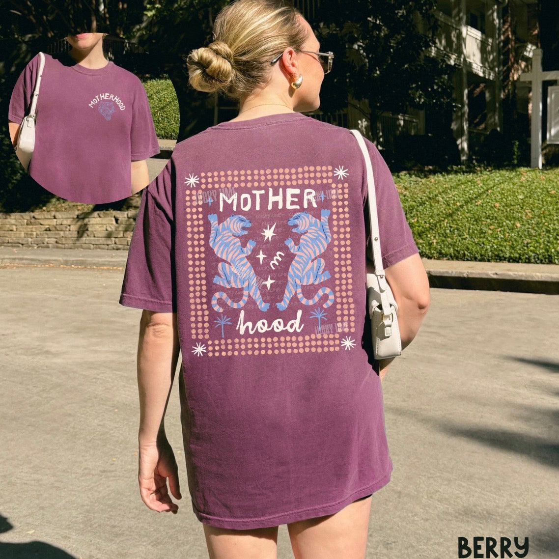 Woman wearing a purple t-shirt with 'Motherhood' design outdoors