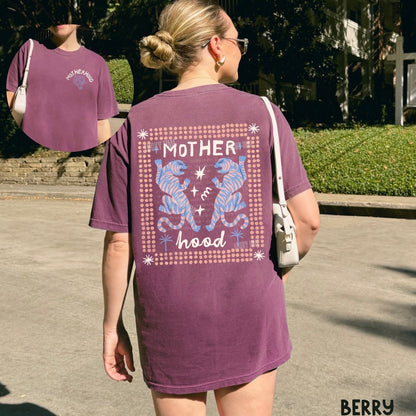Woman wearing a purple t-shirt with 'Motherhood' design outdoors