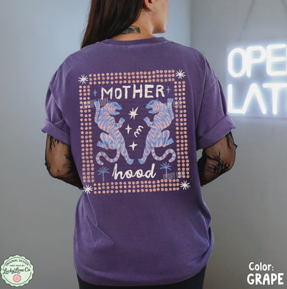 Person wearing a purple t-shirt with a graphic design on the back, standing in front of a neon sign.
