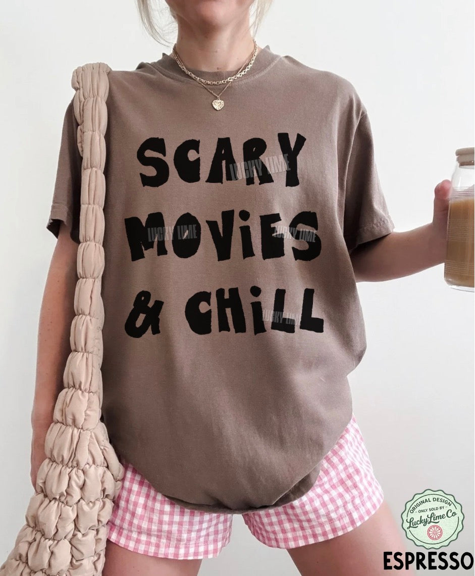 Person wearing a t-shirt with 'Scary Movies & Chill' text, holding a jar of coffee.