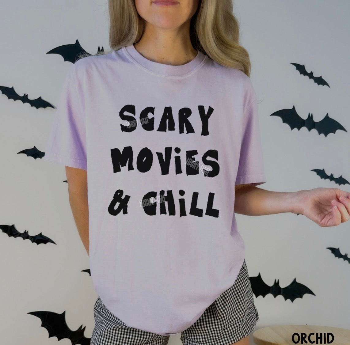Person wearing a 'Scary Movies & Chill' t-shirt with Halloween-themed background