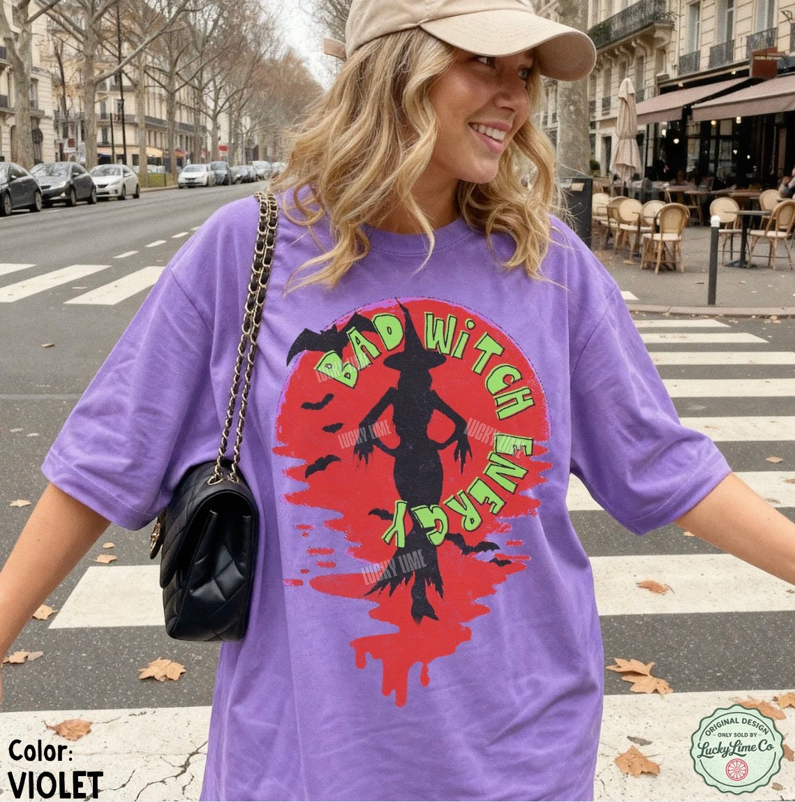 Woman wearing a purple t-shirt with a graphic design on a city street.