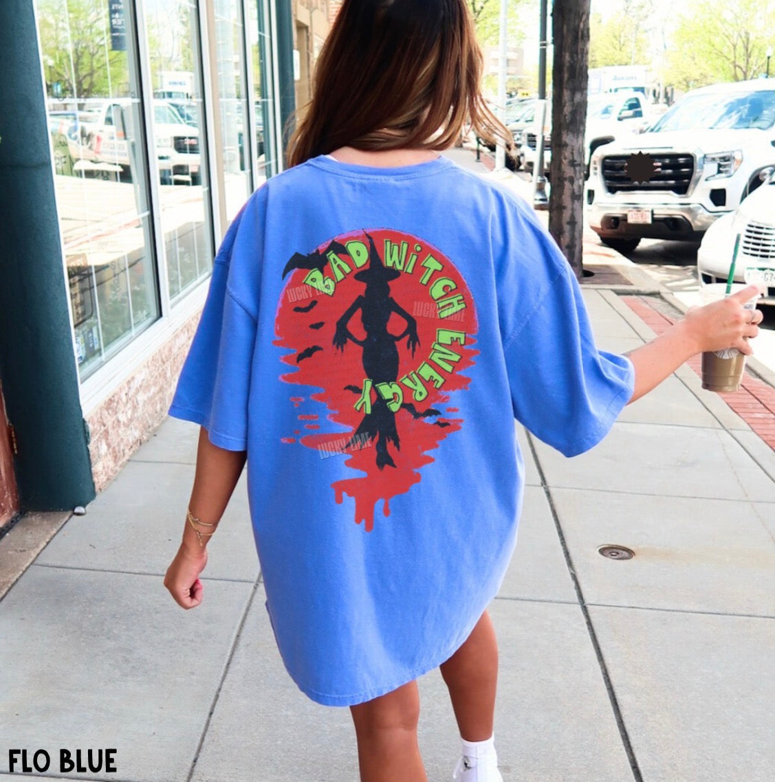 Person wearing a blue oversized t-shirt with a graphic design on a sidewalk.