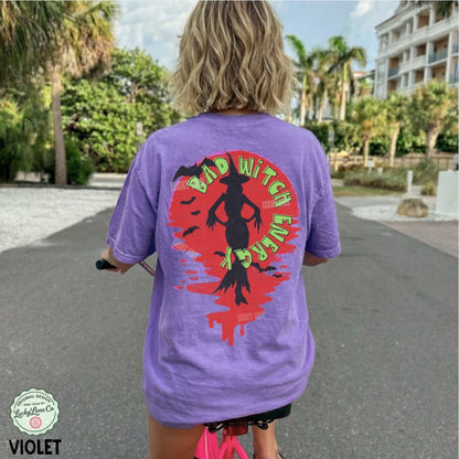 Person wearing a purple t-shirt with a colorful graphic on the back, standing outdoors.