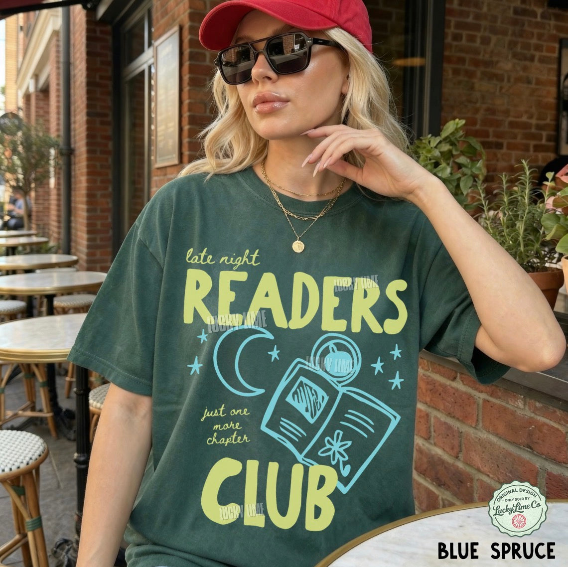 Woman wearing a t-shirt with 'Late Night Readers Club' design outdoors.