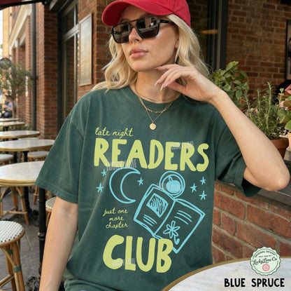 Woman wearing a t-shirt with 'Late Night Readers Club' design outdoors.