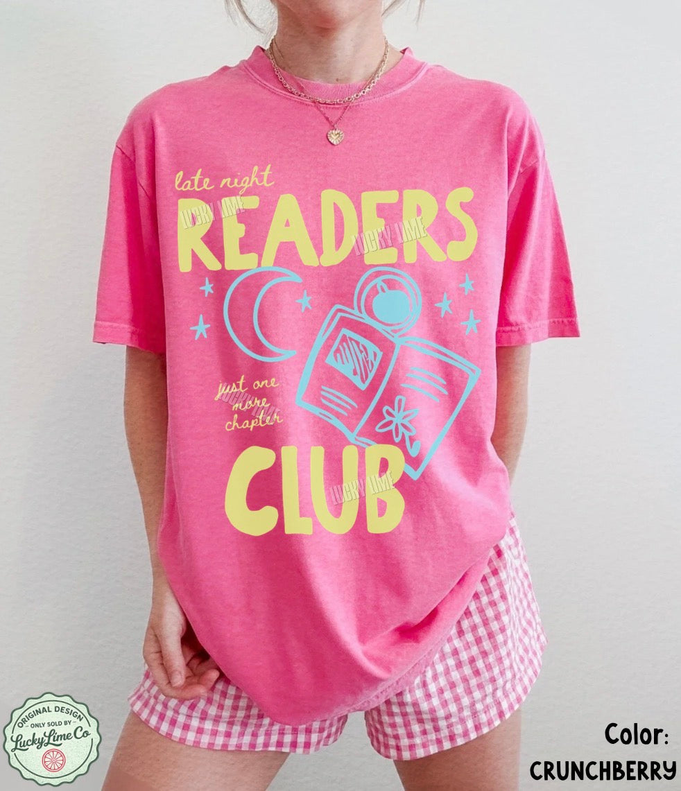 Person wearing a pink 'Late Night Readers Club' t-shirt and shorts with a plain background