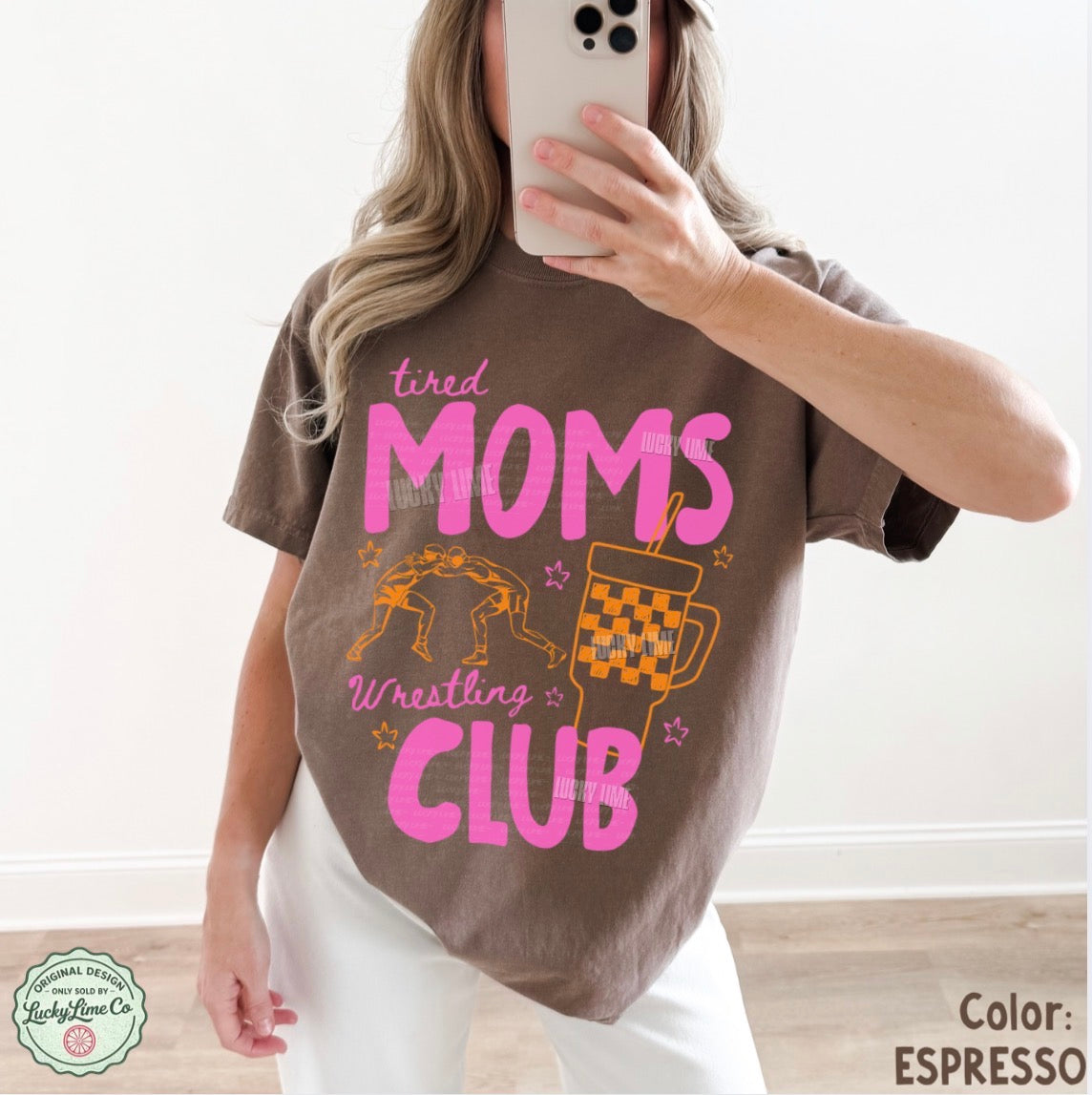 Person wearing a brown t-shirt with 'tired moms wrestling club' text and graphics.