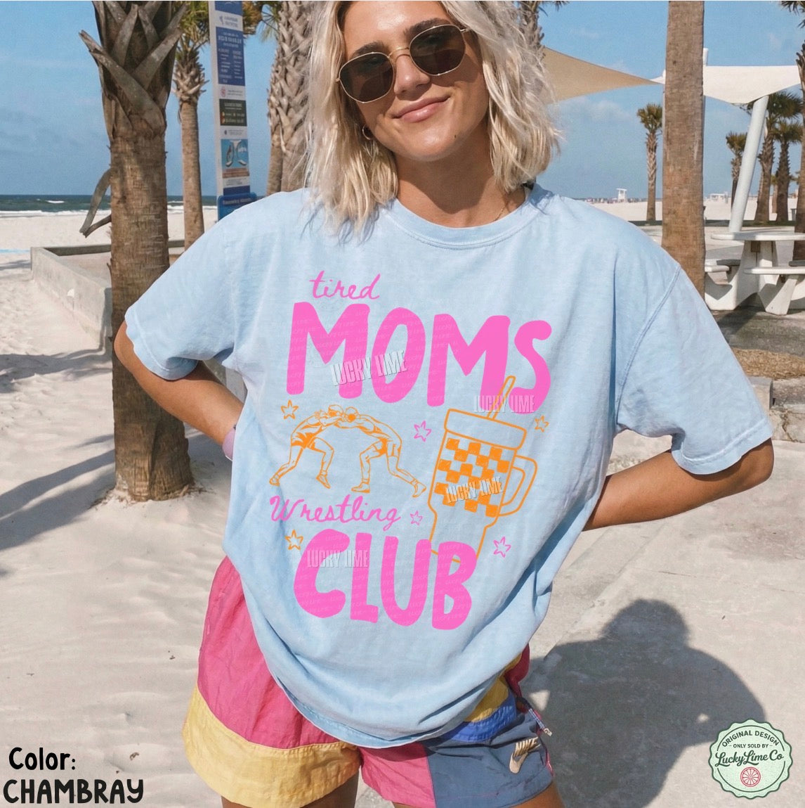 Woman wearing a 'Tired Moms Wrestling Club' t-shirt on a beach.