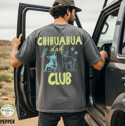Man wearing a t-shirt with 'Chihuahua Dad Club' design, standing next to an open car door in a desert setting.