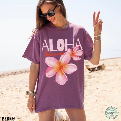 Woman wearing a purple 'Aloha Hawaii' t-shirt with floral designs on a beach.