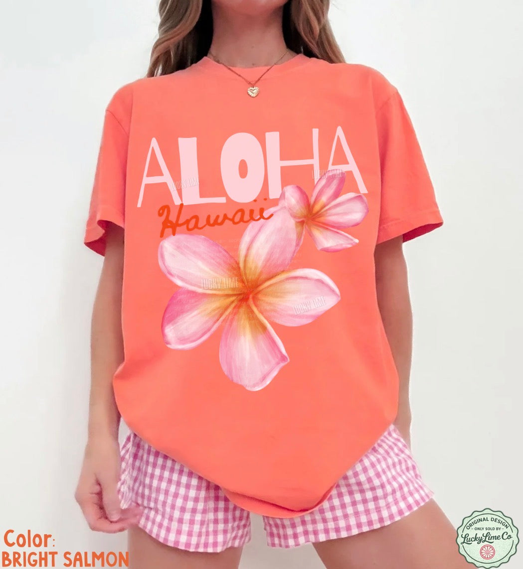 Person wearing a bright salmon-colored 'Aloha Hawaii' t-shirt with a floral design on a plain background.