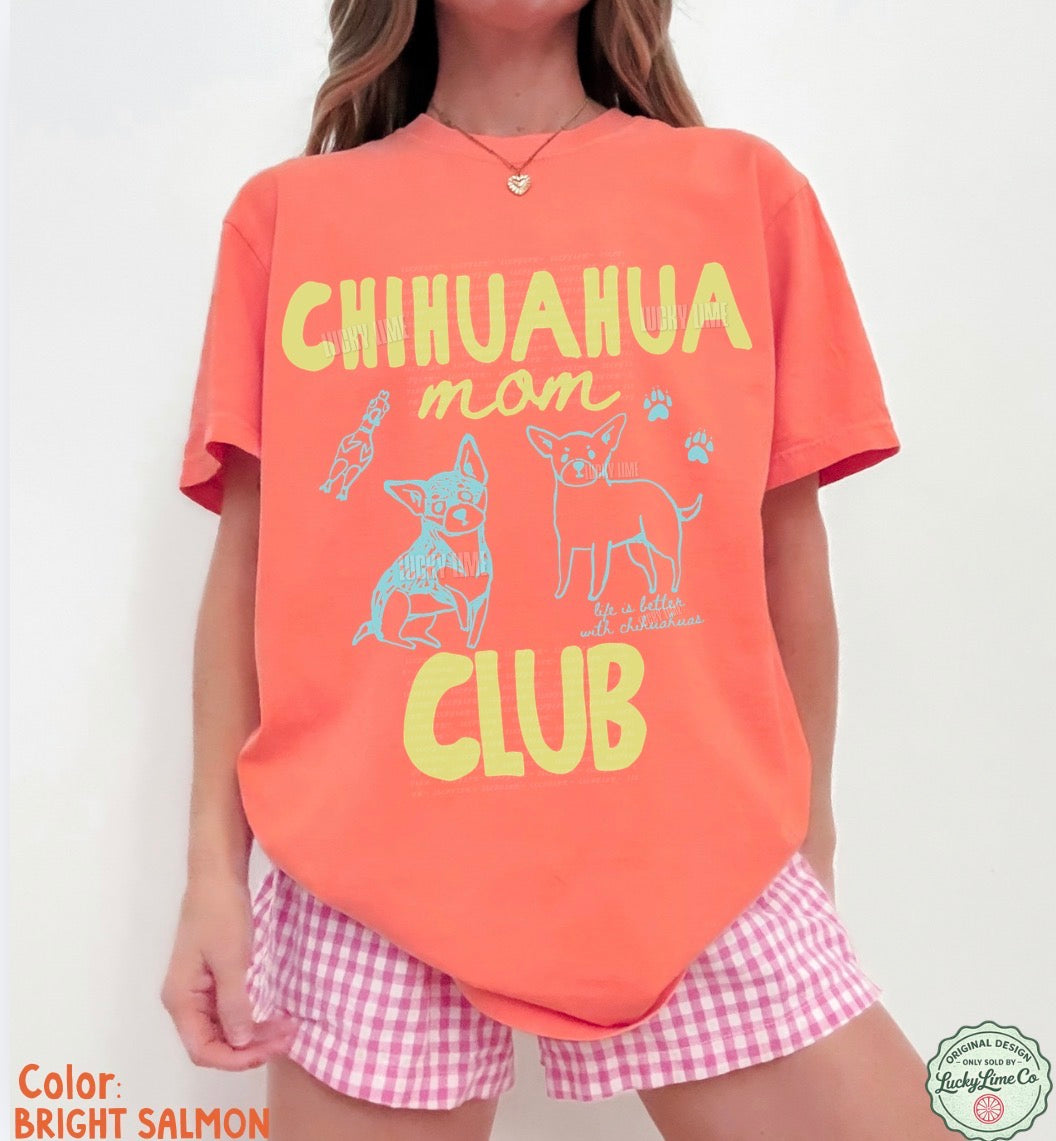 Person wearing a bright salmon t-shirt with 'Chihuahua mom club' text and graphics on a white background.