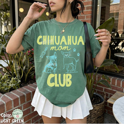 Person wearing a green t-shirt with 'Chihuahua mom club' text and graphics outdoors.