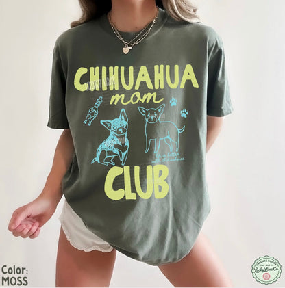 Person wearing a green t-shirt with 'Chihuahua mom club' text and graphics on a plain background