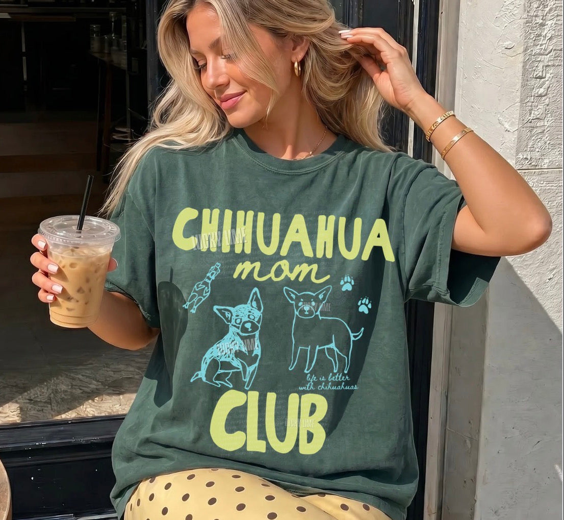 Woman wearing a green t-shirt with 'Chihuahua mom club' text and graphics, holding a drink.
