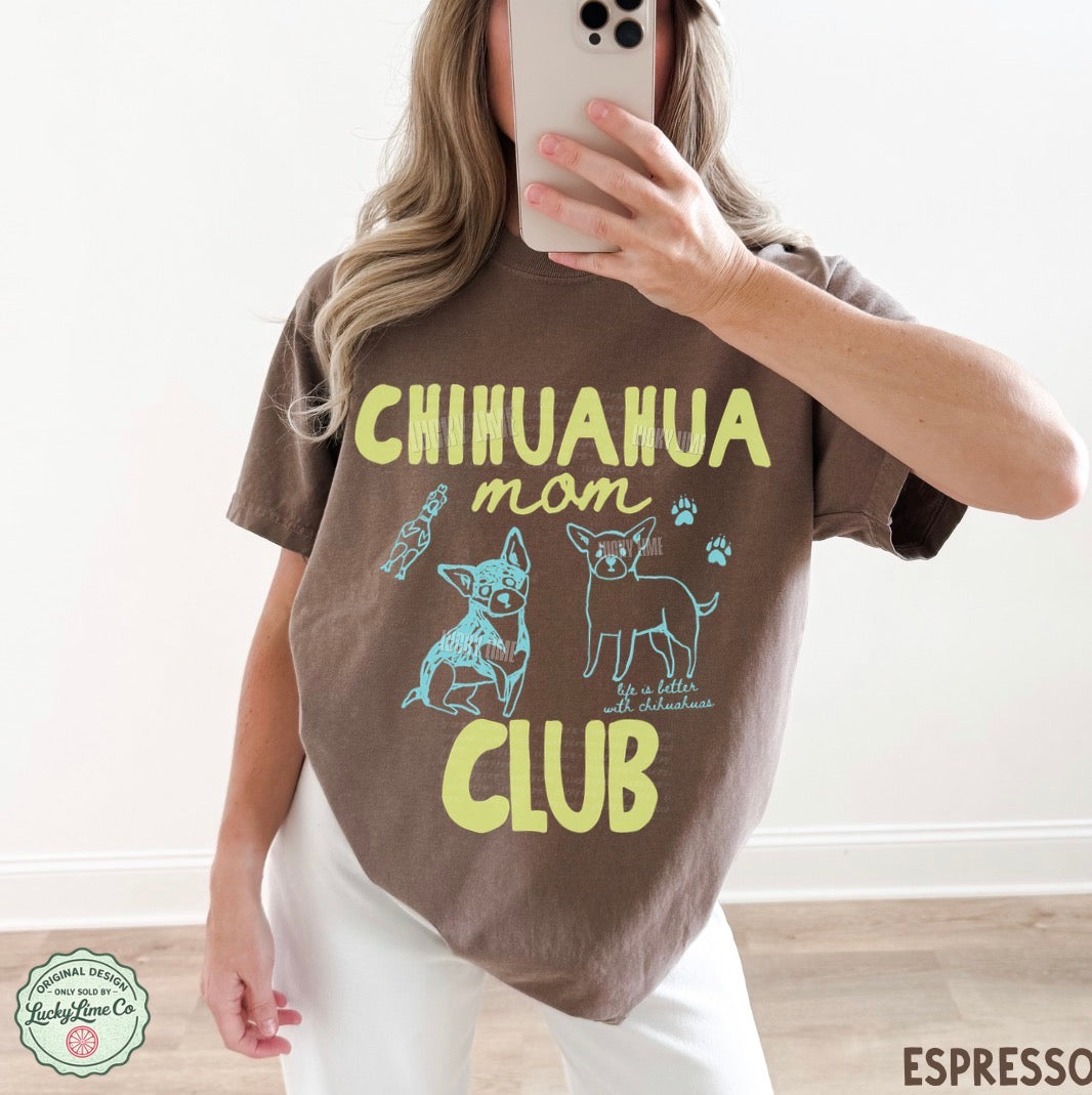 Person wearing a brown t-shirt with 'Chihuahua mom club' text and graphics, taking a selfie.