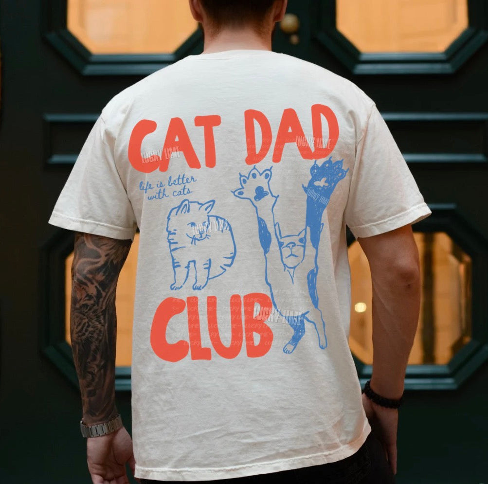 Person wearing a t-shirt with 'Cat Dad Club' design in front of a decorative door.
