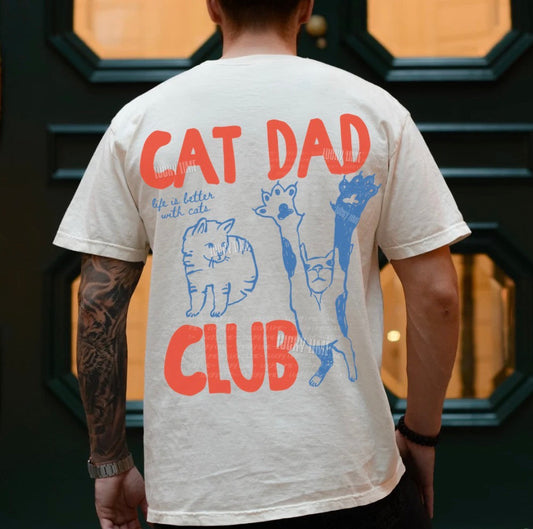 Person wearing a t-shirt with 'Cat Dad Club' design in front of a decorative door.