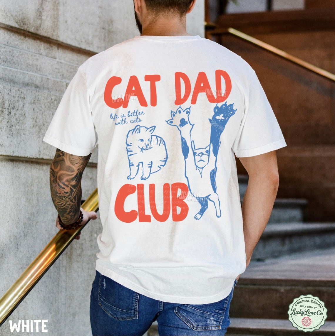 Person wearing a white t-shirt with 'Cat Dad Club' design on the back, standing outdoors.
