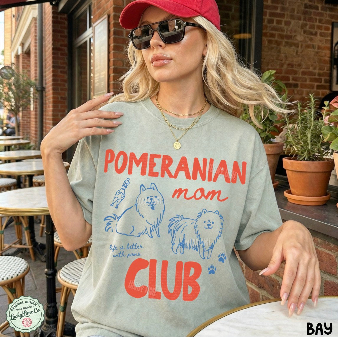 Woman wearing a t-shirt with 'Pomeranian mom club' text and graphics in an outdoor setting.