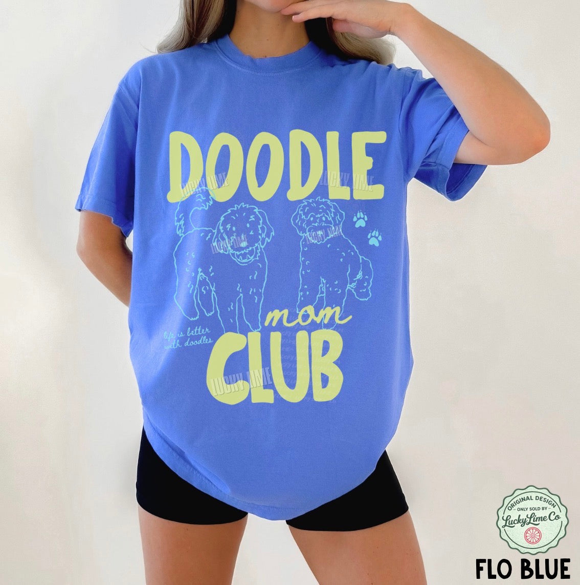 Person wearing a blue t-shirt with 'Doodle mom club' text and dog illustrations.