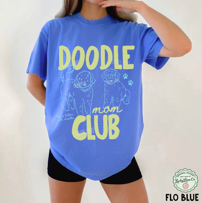 Person wearing a blue t-shirt with 'Doodle mom club' text and dog illustrations.