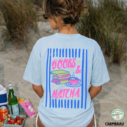 Person wearing a t-shirt with 'Books & Matcha' design on a beach.