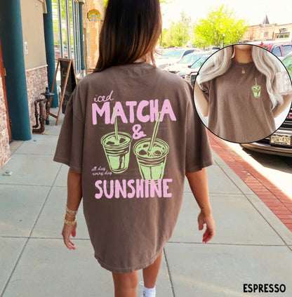 Person wearing a brown t-shirt with 'iced matcha & sunshine' text and graphics, standing on a sidewalk.