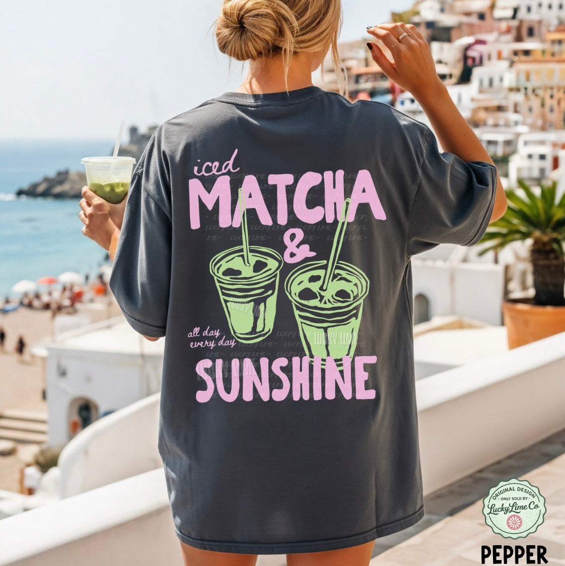 Person wearing a pepper  t-shirt with 'iced matcha & sunshine' text in a scenic location.