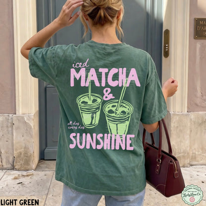 Person wearing a green t-shirt with 'iced matcha & sunshine' text and graphics.