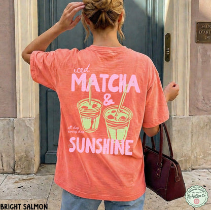 Person wearing a salmon-colored t-shirt with 'iced matcha & sunshine' text and graphics.