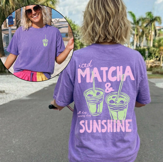 Person wearing a purple t-shirt with 'iced matcha & sunshine' text and graphics.
