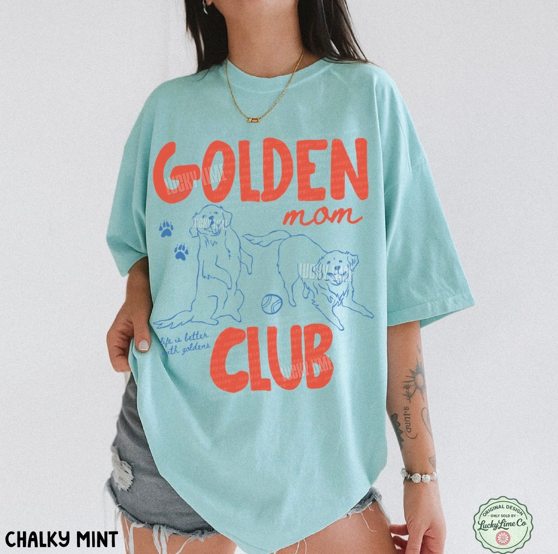 Person wearing a light blue t-shirt with 'Golden Mom Club' text and graphics on a white background