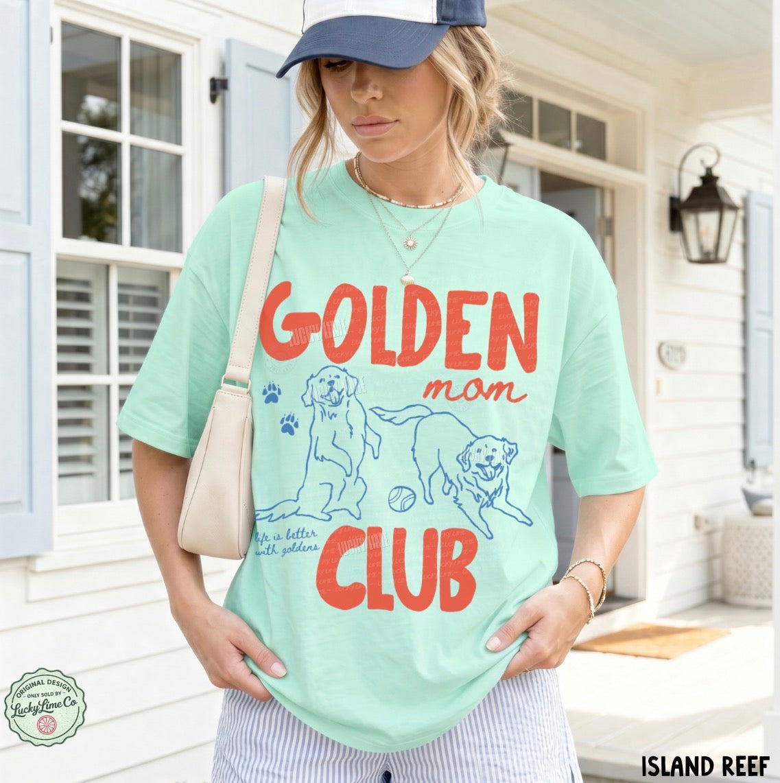 Woman wearing a light green t-shirt with 'Golden Mom Club' text and dog illustrations on a porch.