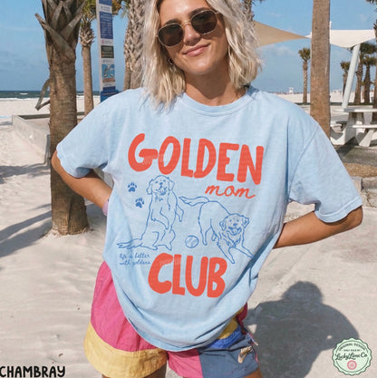 Person wearing a 'Golden Mom Club' t-shirt on a beach